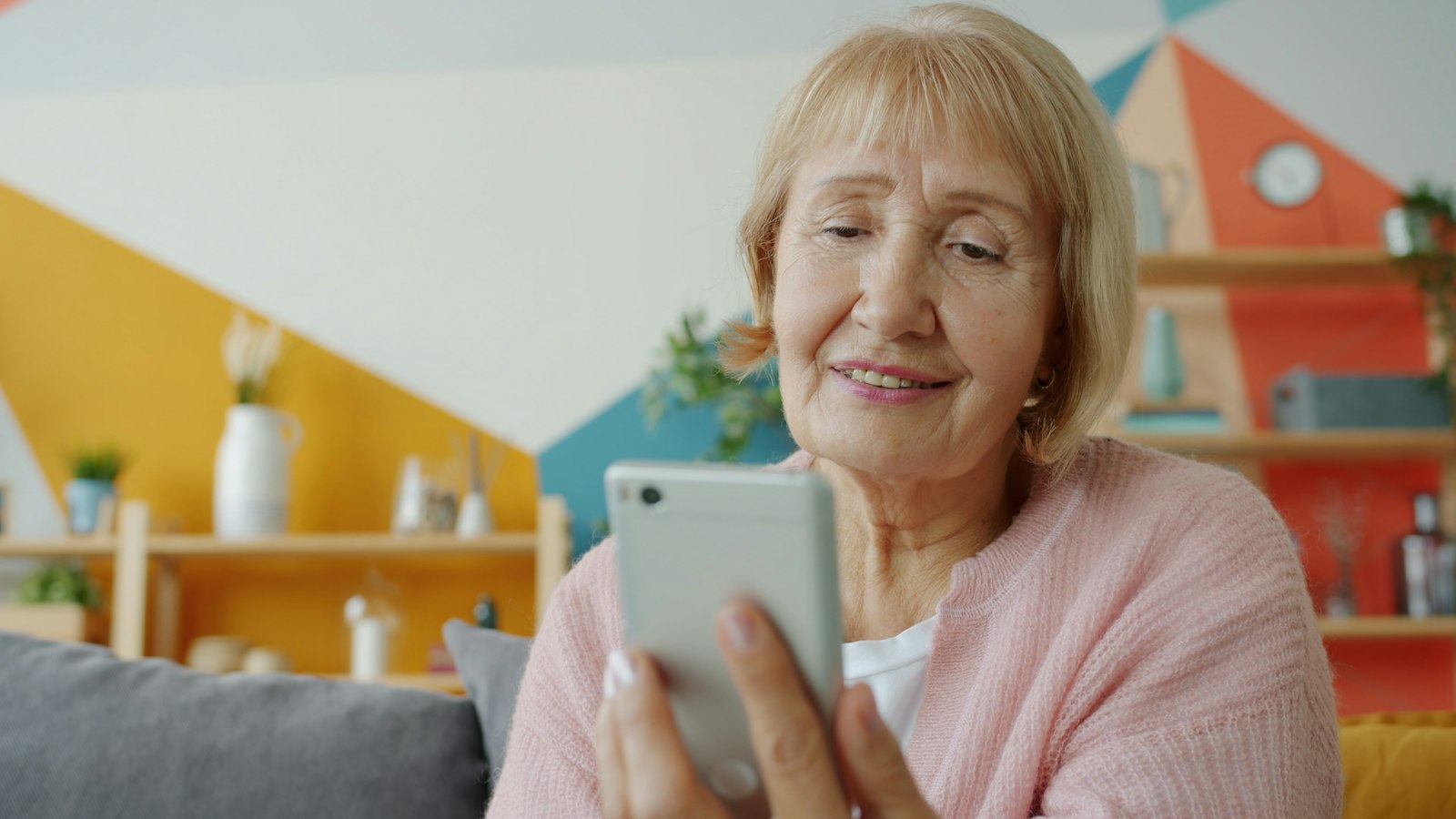 Femeie zâmbind în timp ce folosește un smartphone (imagine ilustrativă)